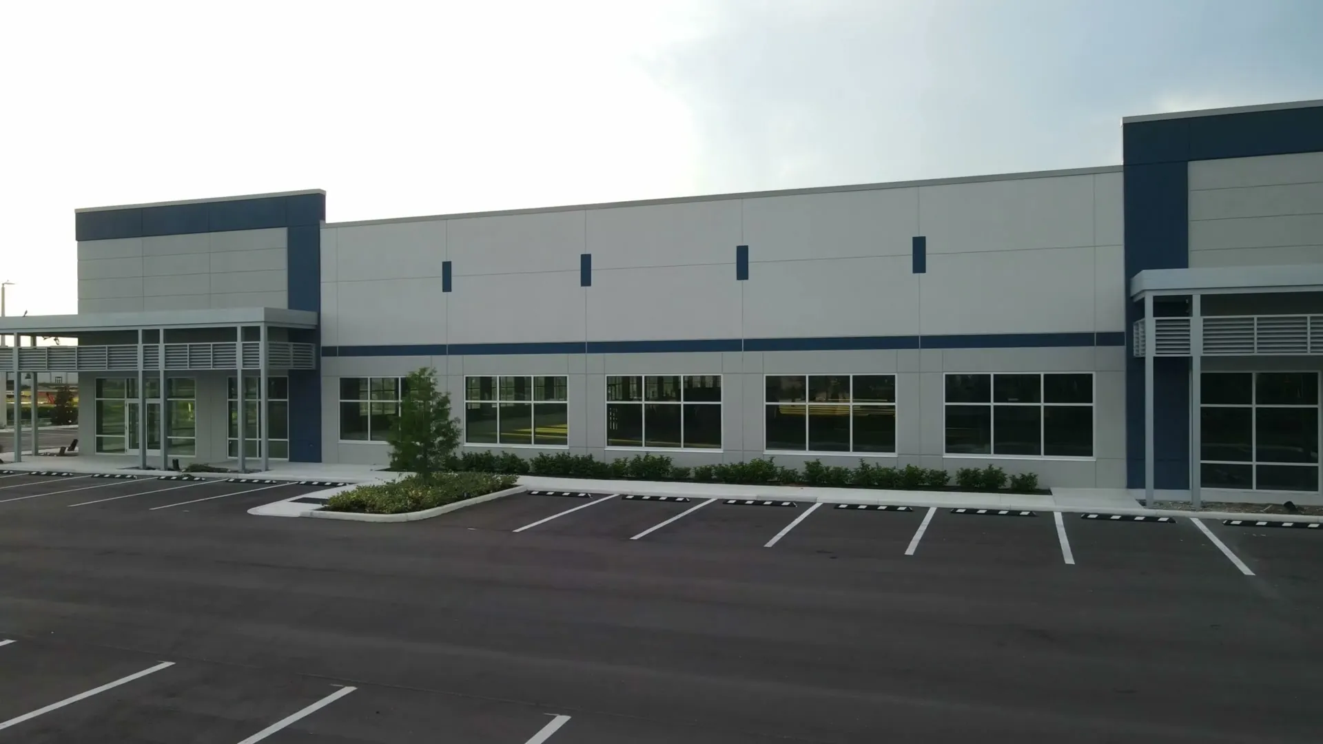 A new single-storey commercial building with grey panels and navy accents, seen from its parking lot.