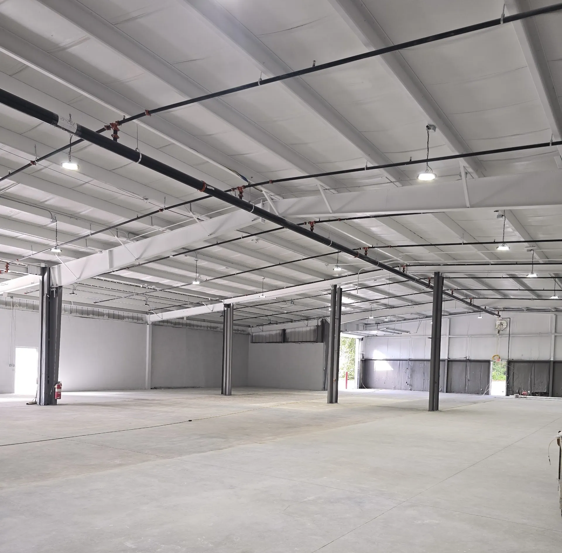 Industrial addition and renovation: a large open warehouse interior with a high open-web joist ceiling.