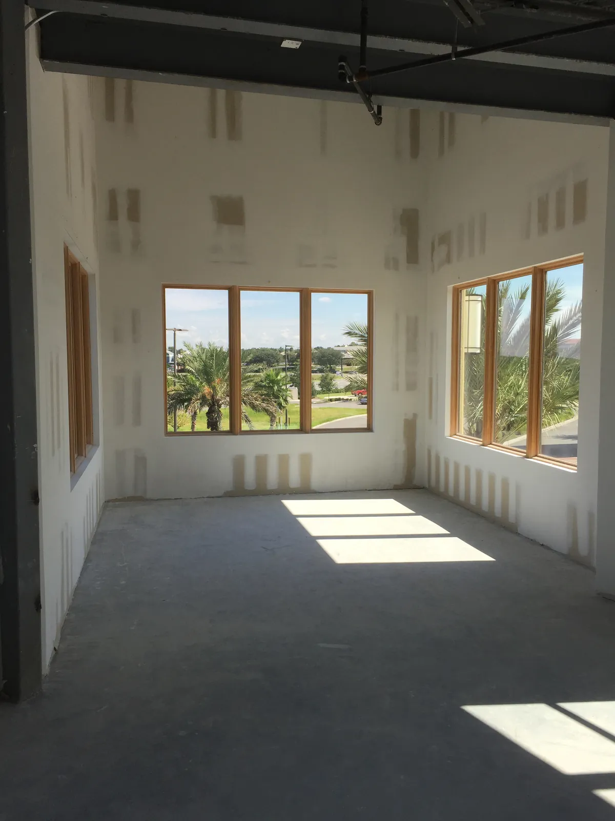 Interior fit-out in progress: drywall hung and taped in a room with windows.