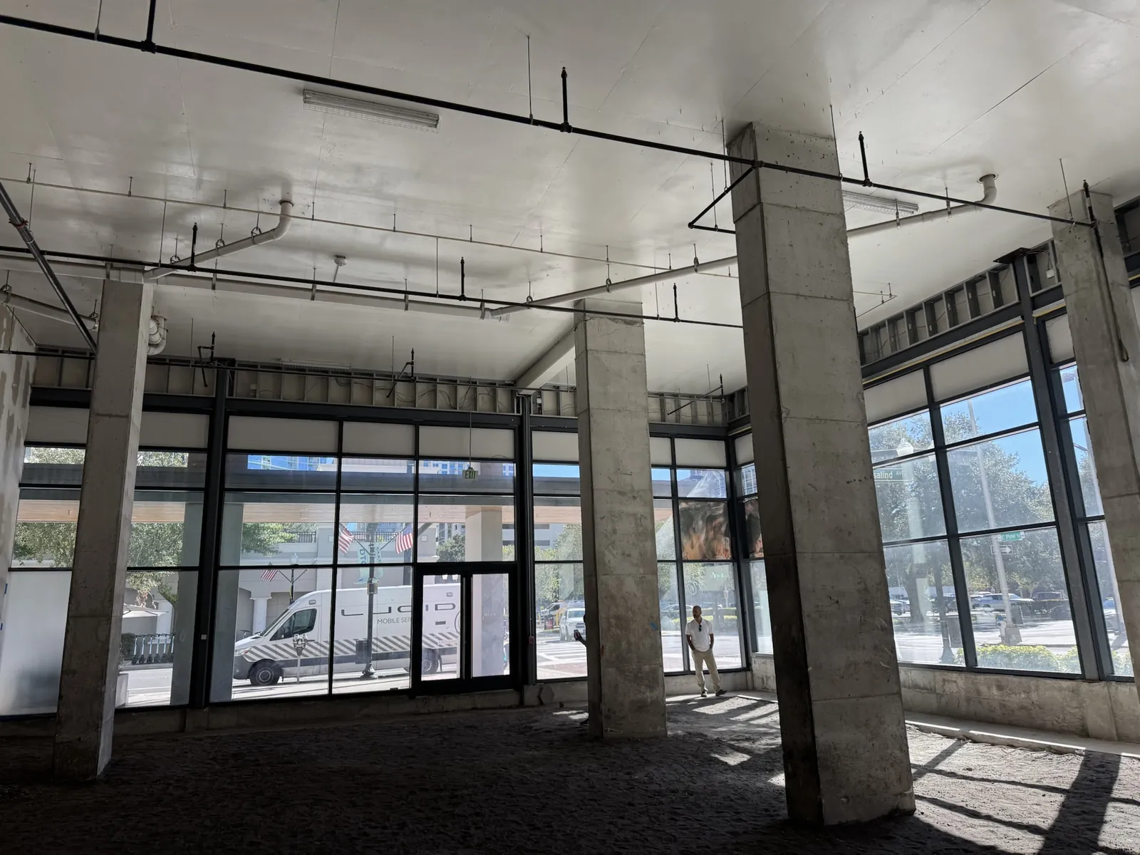 An empty commercial shell space with storefront glazing, columns and an open ceiling.